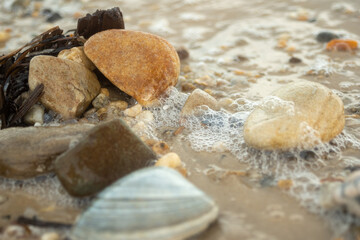 Fototapeta na wymiar Bubbles cling to the pebbles washed by the surf