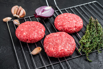 Organic raw ground beef, round patties for homemade burger. Black background. Top view