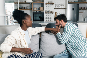 Young couple woman is unhappy while her boyfriend lighting a cigarette because she is against...