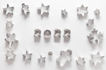 Christmas-themed cookie cutters for gingerbread as frame on white background. New Year creative concept and greeting card. Top view, flat lay. Happy New Year 2022.