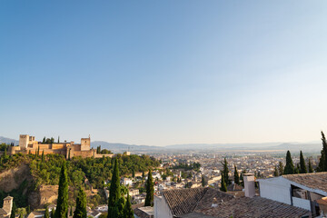Aerial panoramic view of Granada, Andalusia, Spain. On the left the famous Alhambra, on the hill with green trees. Blue sky on the background.