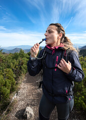 Woman tourist drinks water through a hose from a camelbak while walking. 