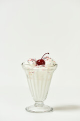 Vanilla sundae ice cream in cup with sweet grains and bing cherry on top isolated on white background