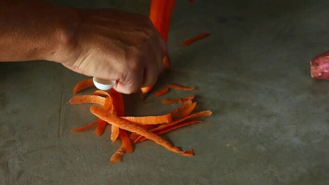 Cook in his kitchen peeling vegetables. Fresh food processed without its peel. Vegan food