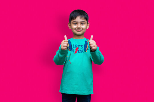 Young little boy thumbs up with both hands on plain color background