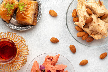 Assortment of Turkish delights with glass of tea on gray background