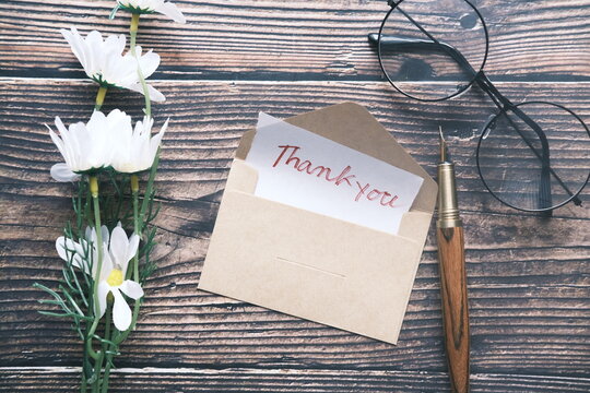 thank you message and envelope on wooden table 