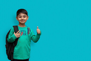 Happy smiling boy with thumb up is going to school. Child with school bag and books. Kid indoors on...