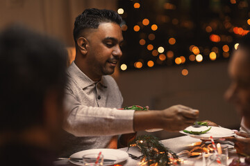 holidays, party and celebration concept - happy man with friends having christmas dinner at home