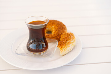 Crispy Turkish traditional bagel, simit with sesame and glass of turkish black tea, turkish breakfast pastry concept. Turkish tea in traditional glass cup. 