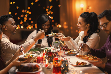 holidays, party and celebration concept - multiethnic group of happy friends having christmas...