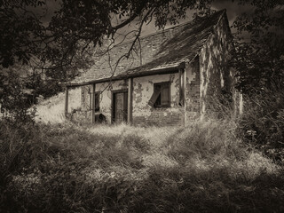 Abandoned and dilapidated wine houses in nature with threatening sky in monochrome.