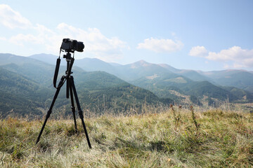 Tripod with modern camera in mountains on sunny day. Professional photography © New Africa