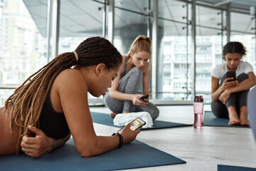 Young black woman use smartphone at workout in gym