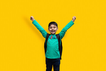 Cute 7 year-old happy boy with school backpack holding books in plain background for education concept