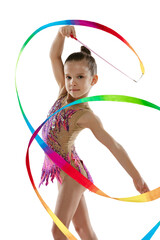 Full-length portrait of little girl, professional rhythmic gymnast training, performing with...