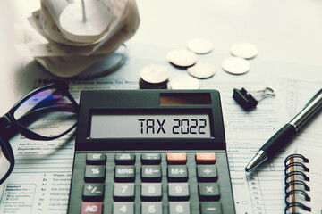 Word Tax 2022 on the calculator. Business and tax concept.Calculator, currency, book, tax form, and...