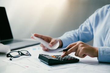 Man using the calculator to calculate domestic bills at home. Young male checking balance and costs...