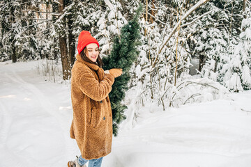 An independent woman prepares for Christmas concept. Young woman carries a Christmas tree in the winter forest