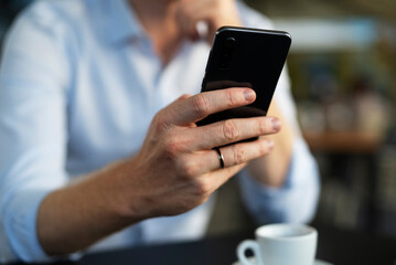 Close up of businessman using the phone in cafe.  Young man enjoying in fresh coffee