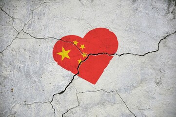 The symbol of the national flag of China in the shape of a heart on a cracked concrete wall.