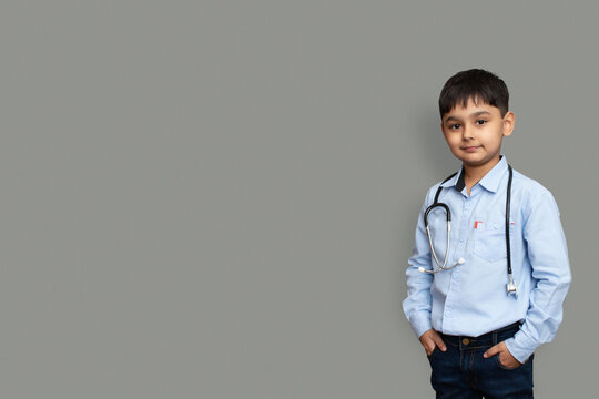 Cute small pakistani asian kid boy wear white shirt with stethoscope playing doctor, happy funny little mixed race preschool child pretending pediatri