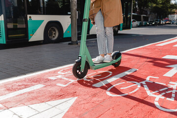 traffic, city transport and people concept - woman riding electric scooter along red bike lane with...