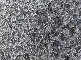 Transparent ice crystals texture cracked background on the river in winter season,closeup,top view.