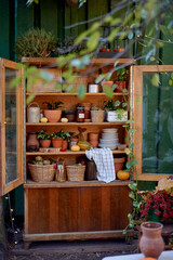 Country wardrobe against a green wall with baskets, towels, pots and jars.