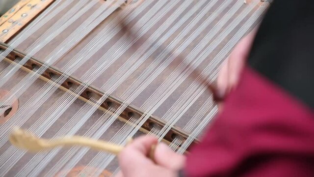 Close up of dulcimer string and wooden bat. Playing traditional musical instruments. Closeup hand play hammered dulcimer