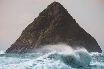 Beautiful foamy ocean waves with pointy forest mountain in the background