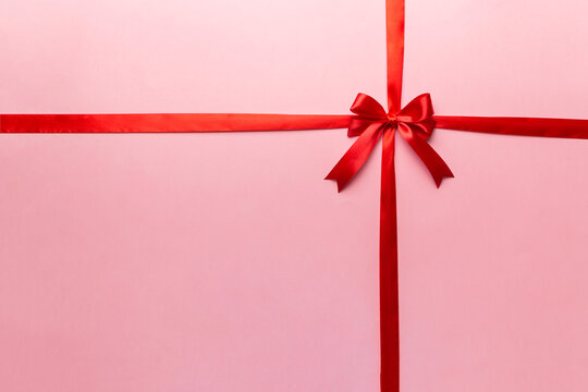 Top view of Red ribbon rolled and red bow isolated on colored background. Flat lay with copy space