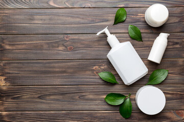 Organic cosmetic products with green leaves on wooden background. Copy space, flat lay