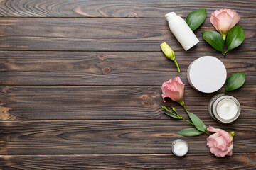 Composition with cosmetic products and beautiful roses on wooden background. Copy space, flat lay