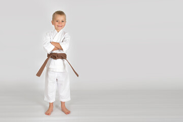Little kid boy in karate kimono isolated on white background. The concept of martial arts, karate, judo,  sports since childhood, discipline. Defence concept with copy space.