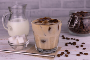 Obraz na płótnie Canvas Iced latte coffee in a glass on a white wooden background.
