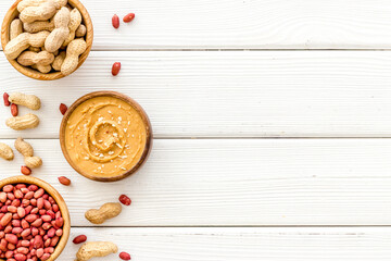 Bowls of homemade peanut butter and nuts on table, top view