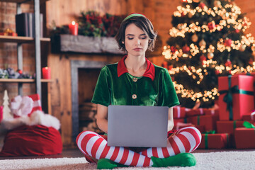 Portrait of attractive girl elf sitting using laptop writing email staying at home modern loft...
