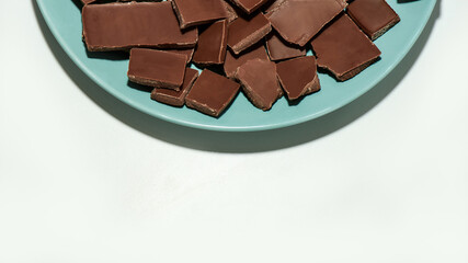 Cropped view of crushed dark chocolate bars stack on a plate isolated over white background