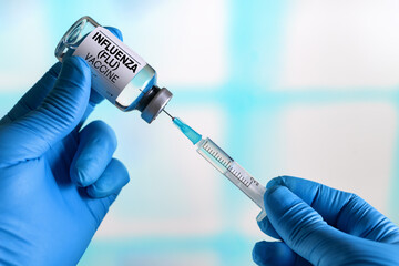 doctor preparing a dose of the vaccine for Virus Influenza Flu Grippe. doctor with Influenza (Flu) vaccine bottle for the annual flu disease prevention campaign