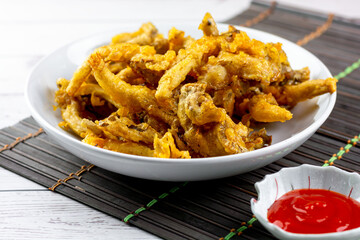 Snack food concept. Deep-fried crispy oyster mushroom on a white plate with red hot chili dipping...