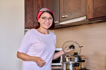 Portrait of a middle aged smiling woman preparing food in the kitchen