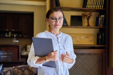 Portrait of a mature business woman in glasses with a laptop in her hands