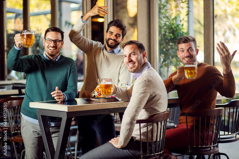 Wall mural group of friends drinking beer in pub