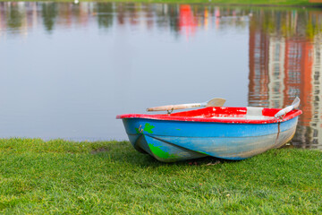 Wooden boat on the shore of a transparent lake in the park on a warm clear day