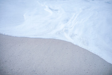 the foam wave on the sandy beach. soft waves in the coastline that feels tranquil and enjoyable for relaxation.