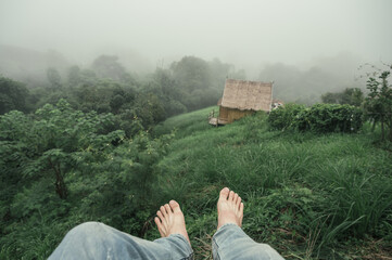 Barefoot man wearing jean hanging on mountain in foggy at rainforest