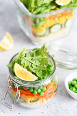 Glass jar with fresh raw vegetables and couscous groats. Healthy Meal Prep - recipe preparation photos. Healthy vegan dishes in glass containers. Weight loss food concept. Salad in a jar.