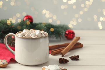Delicious hot chocolate with marshmallows and Christmas decor on white wooden table, space for text