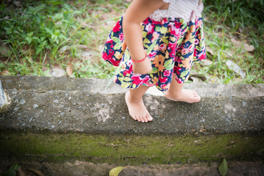 Young girl's feet walking on concrete . Focus on the spot.
